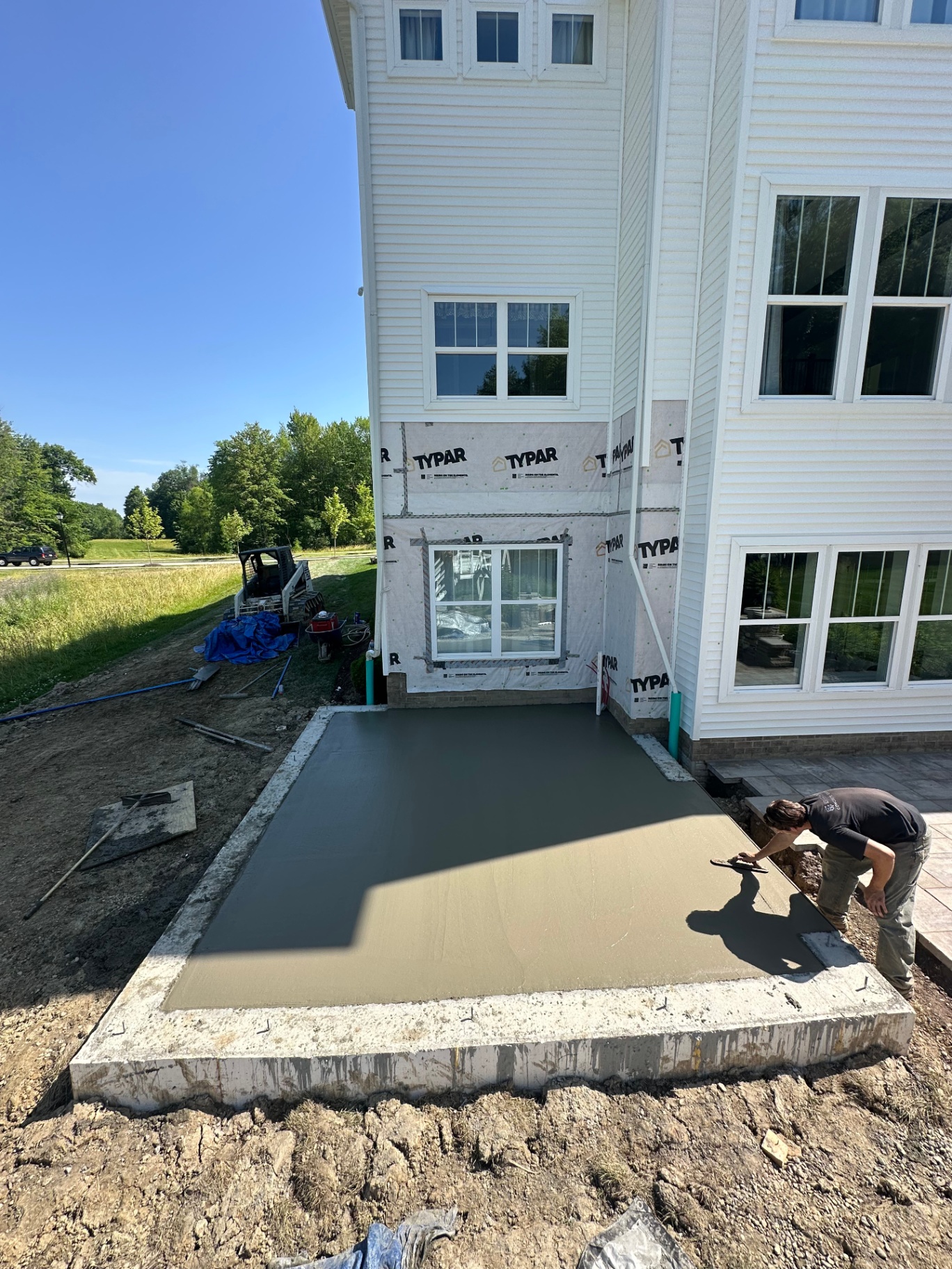 Crew finishing a freshly poured concrete sidewalk along a new home foundation in Richfield, Ohio