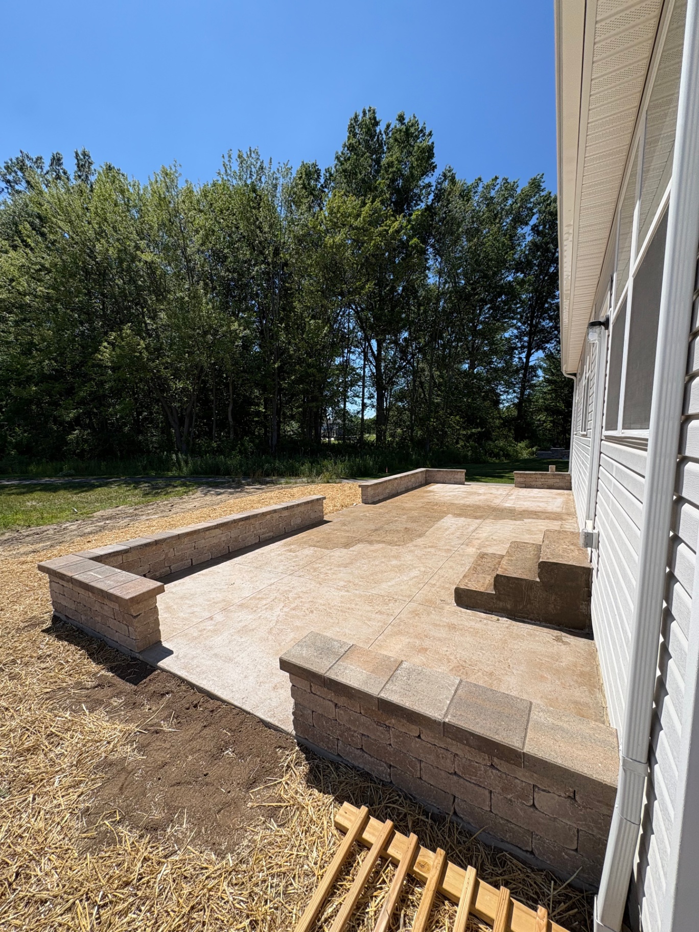 Stamped concrete patio with stone seat walls and planter at a Bath, Ohio home by Edgewater Company
