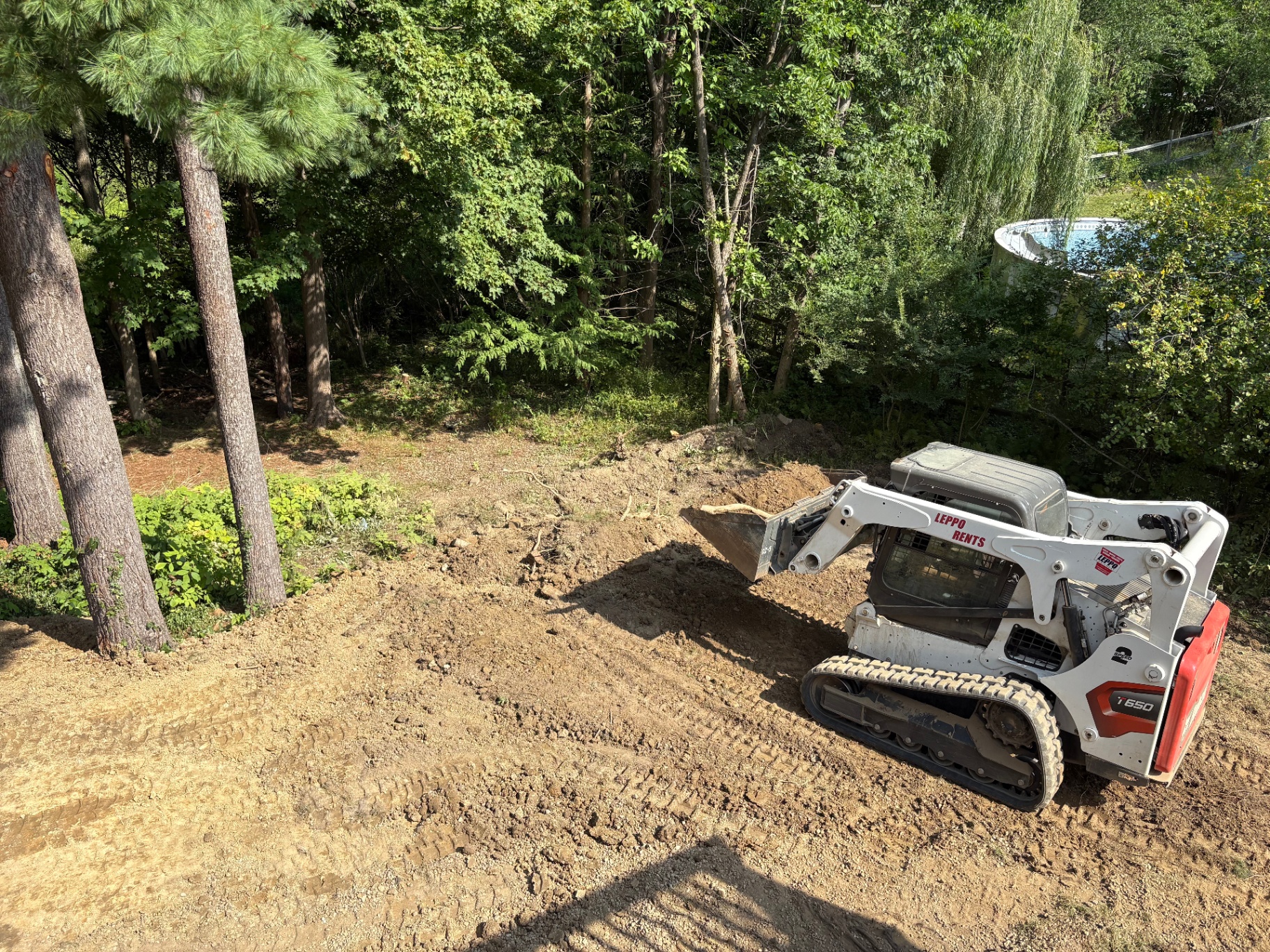 Compact track loader excavating and grading a backyard pool area in Brecksville, Ohio