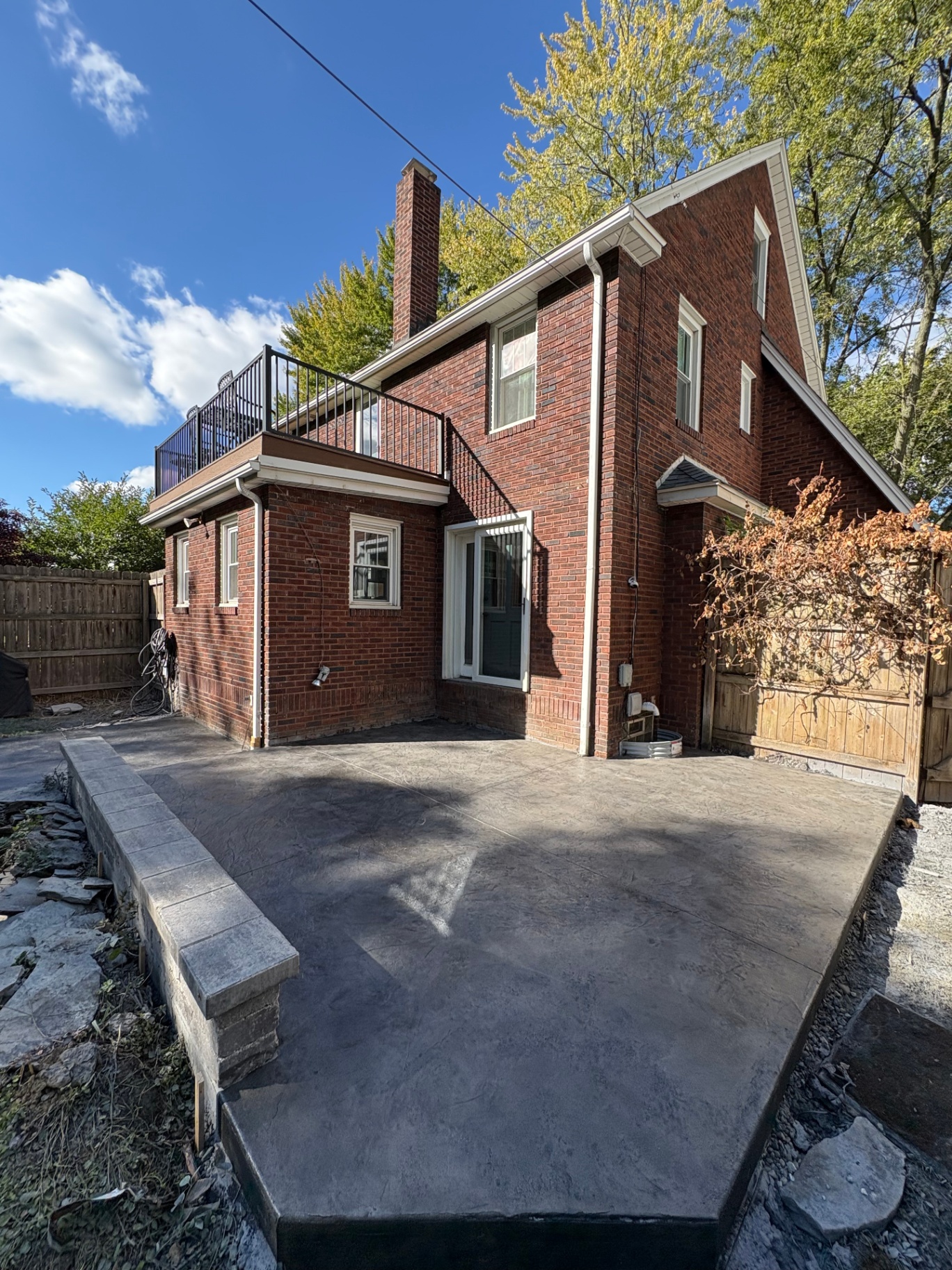 Large stamped concrete patio with stone border wall at a brick home in Akron, Ohio